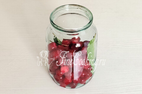 Литровая банка с вишней с косточками и вишнёвыми листьями. Ягоды наколоты зубочисткой.